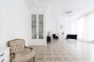 Luxury white interior of living spacious room with elegant chic furniture and high windows.