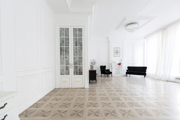 Luxury white interior of living spacious room with elegant chic furniture and high windows.