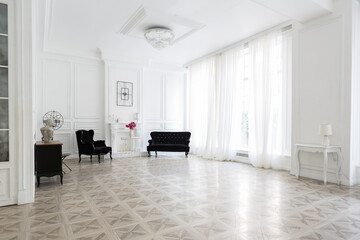 Luxury white interior of living spacious room with elegant chic furniture and high windows.