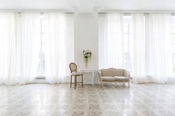 Luxury white interior of living spacious room with elegant chic furniture and high windows.