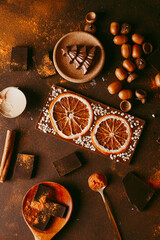 Candied orange slices in chocolate lie on a dark brown background, next to Cutlery.