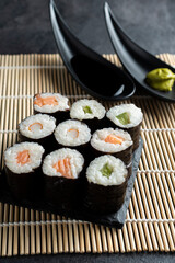 Various kinds of sushi served on black stone plates.