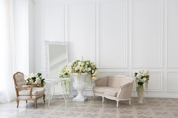 Luxury white interior of living spacious room with elegant chic furniture and high windows.