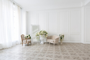 Luxury white interior of living spacious room with elegant chic furniture and high windows.