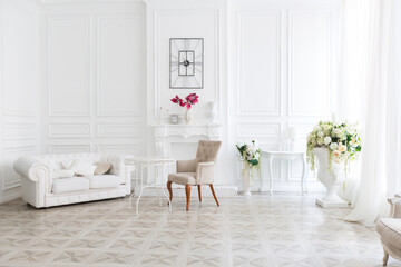Luxury white interior of living spacious room with elegant chic furniture and high windows.