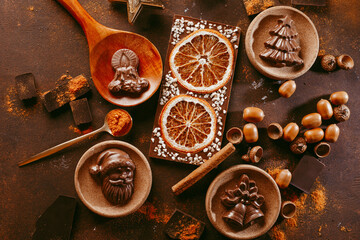 Christmas chocolate figures Santa Claus, Christmas tree, bells, candle are on the dark table