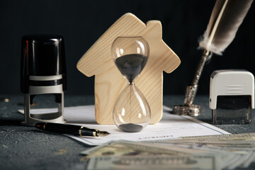 Model of house, money and hourglass close-up. Concept of mortgage or rent.