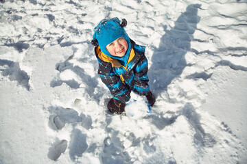 Fototapeta na wymiar funny little boy playing with snow in the winter