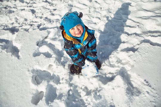 funny little boy playing with snow in the winter