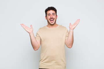 young man feeling happy, excited, surprised or shocked, smiling and astonished at something...