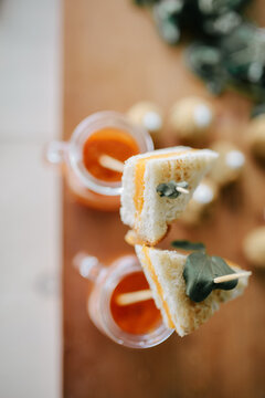two mini grilled cheese sandwiches served on skewers in glass mugs of tomato soup