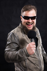 Bearded emotional rock singer with micriphone studio portrait.