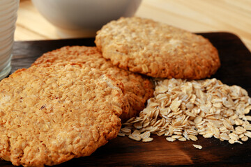 Oat cookies and oat flakes on wooden surface