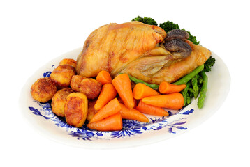Roasted whole Guinea fowl with roast potatoes and fresh vegetables isolated on a white background