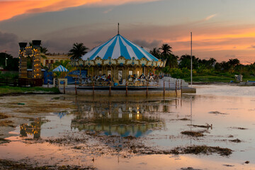 Sunset landscape on the beach with a carousel in the background, golden hour, vacation, travel,...