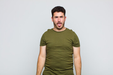 young man feeling disgusted and irritated, sticking tongue out, disliking something nasty and yucky
