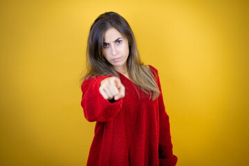 Young beautiful woman wearing red sweater over isolated yellow background pointing to the front with finger