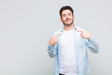 young man looking proud, arrogant, happy, surprised and satisfied, pointing to self, feeling like a...