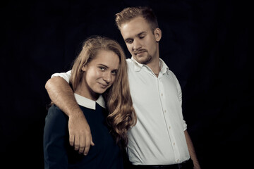 Young beautiful couple studio portrait on black background.