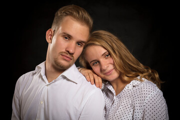 Young beautiful couple studio portrait on black background.