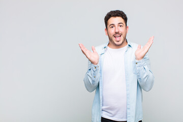 young man feeling happy, excited, surprised or shocked, smiling and astonished at something...