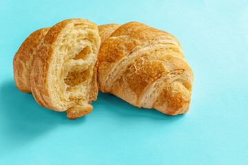 freshly baked two flavorful crispy croissants on a blue surface