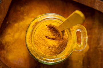 ground turmeric in a glass jar on wooden background