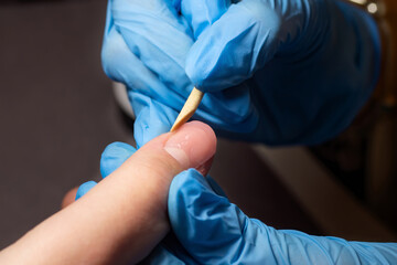 manicurist in blue gloves forms the nail plate using acryl gel. Professional manicure in a beauty salon. Hand care concept