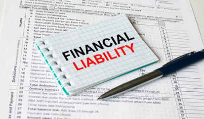 Obraz premium Notepad with text Financial Liability lying on financial tables with a pen