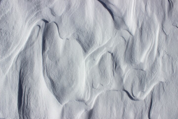 Natural white background. Snowy surface with waves formed by the wind. Abstract background.