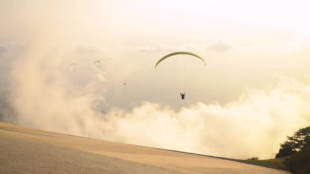 Paraglider practicing the sport of paragliding in the mountain at sunset