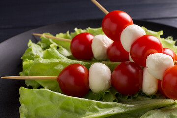 Italian caprese salad with mozzarella balls and skewered tomatoes