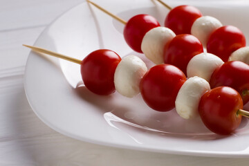Italian caprese salad with mozzarella balls and skewered tomatoes