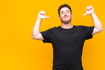 young man feeling proud, arrogant and confident, looking satisfied and successful, pointing to self