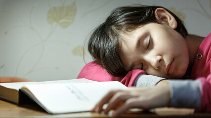 Girl fell asleep doing homework in the evening.