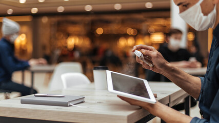 close up . young man spraying antiseptic on his digital tablet