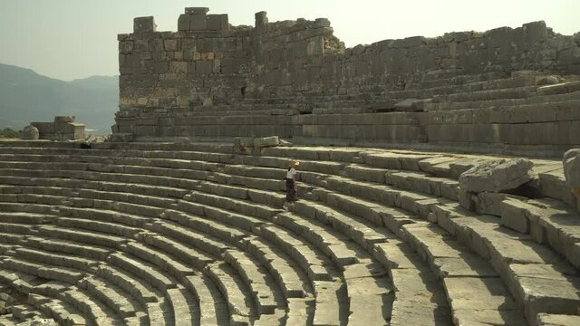 Ruins of ancient theater Xanthos ancient city. Woman traveler walk and explore of the ancient city