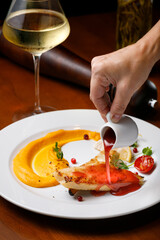 Fried fish with with berry sauce on a white plate with a glass of white wine