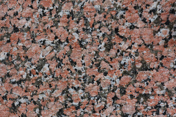Natural pattern on the stone. The texture of the pale pink slice of granite with small black, white and transparent blotches.