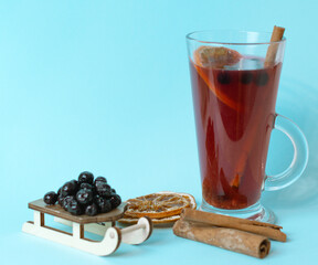 herbal tea with chokeberry, cinnamon and dried oranges on blue background, aronia berry is effective in combating COVID-19 virus
