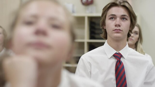 Secondary school students listen in class, depressed struggling boy looks sad