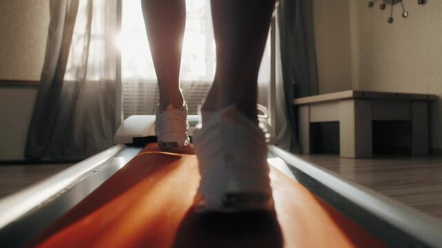 Close Up athlete's foot running on treadmill at home. Back view of legs having workout on treadmill. Stay healthy at home - During the COVID-19 lockdown