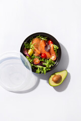take away box with salmon salad with an avocado