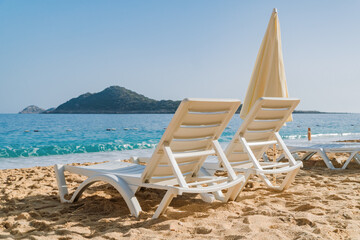 Two beach chairs and umbrella on the beautiful sand beach waiting for someone to come relax. Travel, holidays and resort concept.