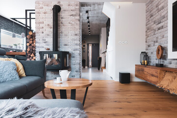 Stylish living room interior with wooden floor, brick wall and fireplace