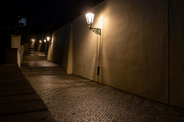 
sidewalk with cobblestones for pedestrians and light from street lights in the center of Prague at night