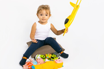 The girl plays with a yellow plane and looks at the camera. Gender stereotypes.