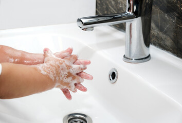 Little boys washing hands in bathroom very thoroughly. Washing hands. Baby hands washing with soap foam on background of water flowing from fauce.