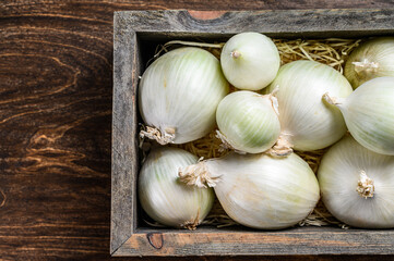 White raw onion in wooden box. Wooden background. Top view