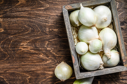 White raw onion in wooden box. Wooden background. Top view. Copy space